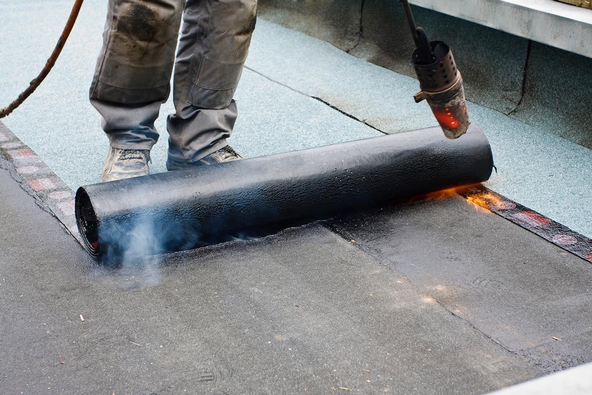 A person is using a torch to roll a roof.