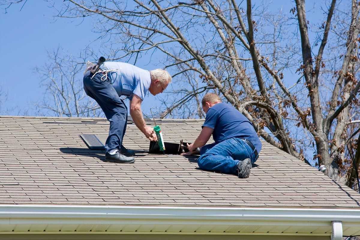 Two men are working on the roof of a house.