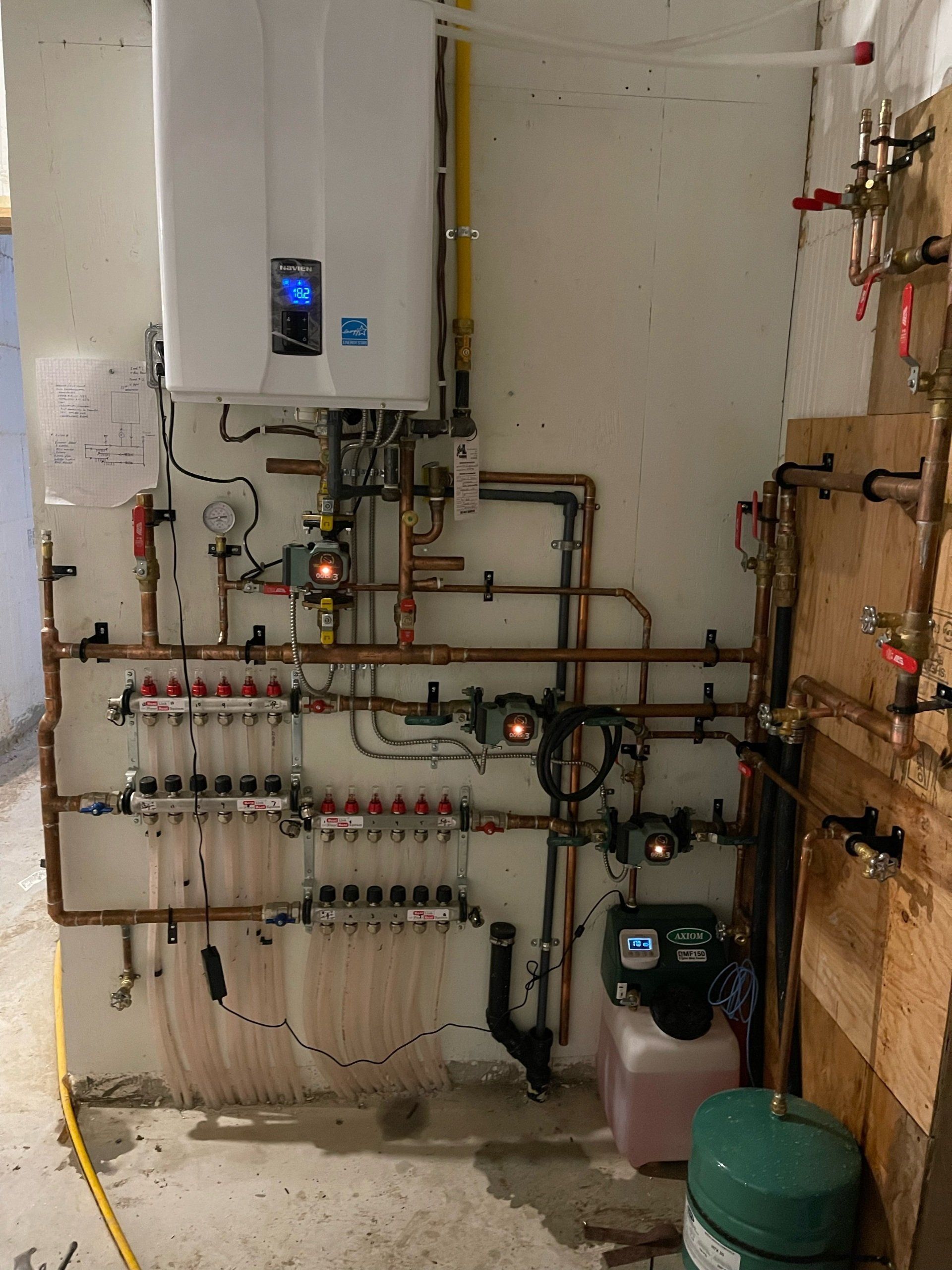 A room with a lot of pipes and a boiler on the wall