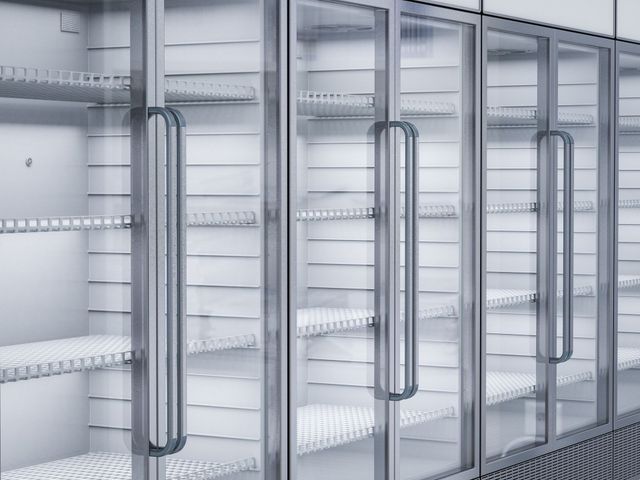 Empty glass-door display refrigerators in a bright store aisle