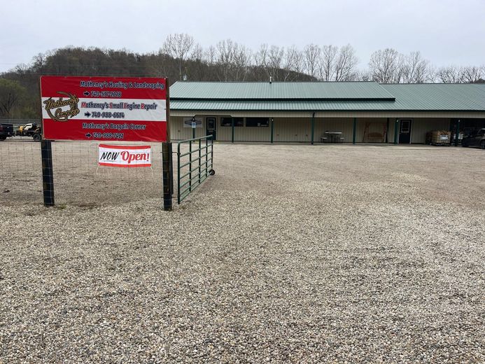 A red sign is in front of a building in a gravel lot.