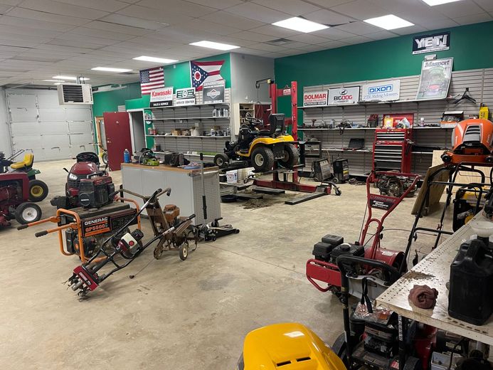 A large room filled with lots of lawn mowers and snow blowers.