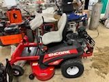 A red lawn mower is sitting on top of a pile of other lawn mowers.