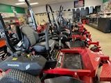 A row of lawn mowers are lined up in a store.