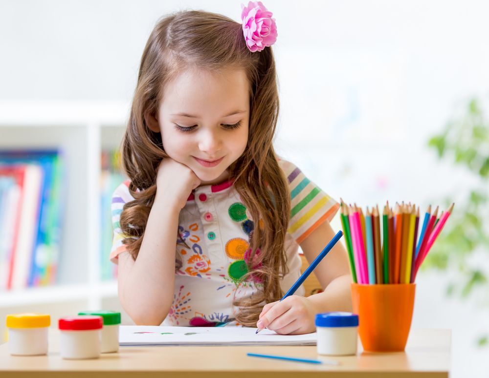 Little Girl Is Sitting At A Table Drawing With A Pencil — Al Roberts Education Centre in Wynnum West, QLD