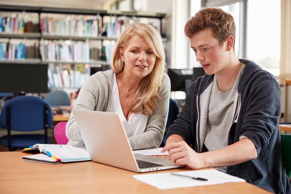 A Woman Is Teaching a Boy how To Use a Laptop Computer — Al Roberts Education Centre in Wynnum West, QLD