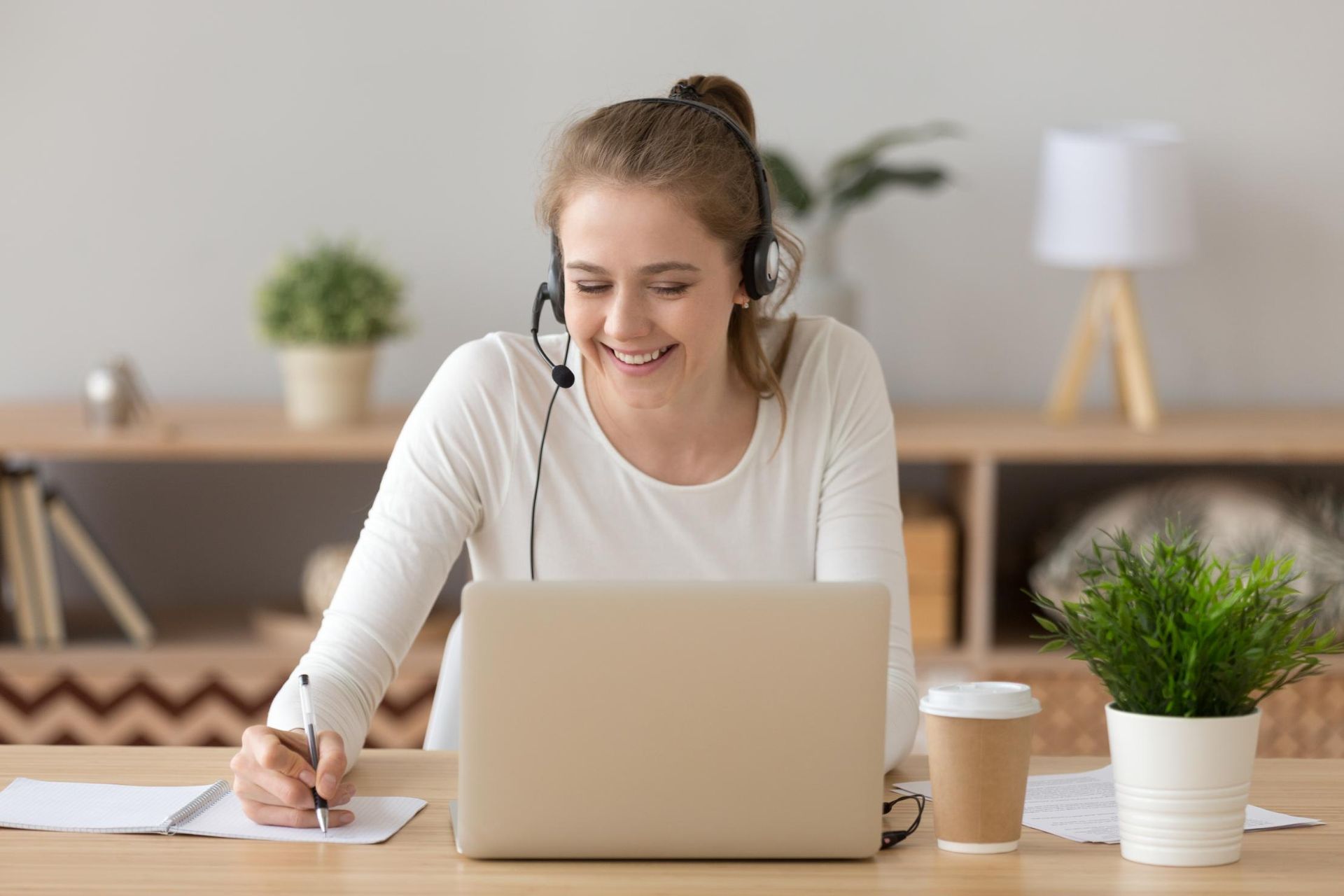 A Woman Wearing Headphones Is Sitting at A Desk Using a Laptop Computer — Al Roberts Education Centre in Wynnum West, QLD