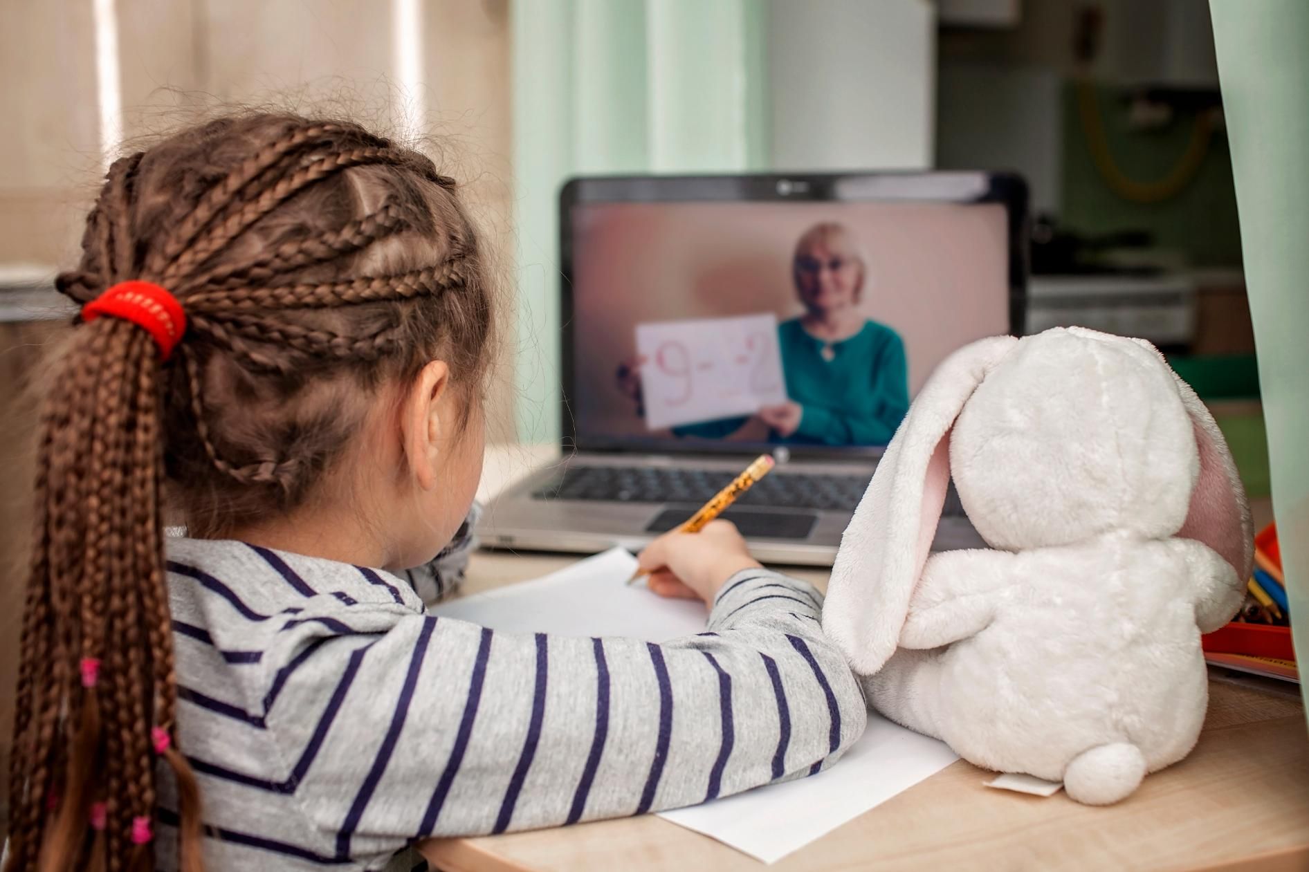 A Little Girl Is Sitting at A Desk with A Stuffed Bunny and A Laptop — Al Roberts Education Centre in Wynnum West, QLD