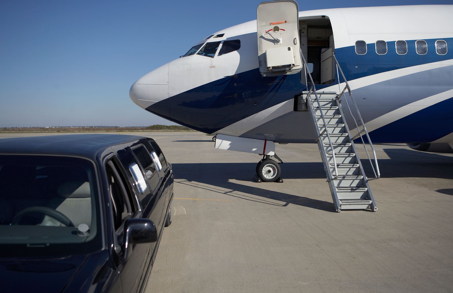 A limousine is parked in front of a private jet