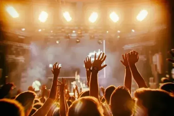 A crowd of people are raising their hands in the air at a concert.