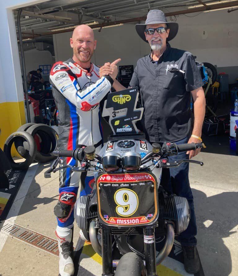 Two men standing next to a motorcycle with the number 9 on it