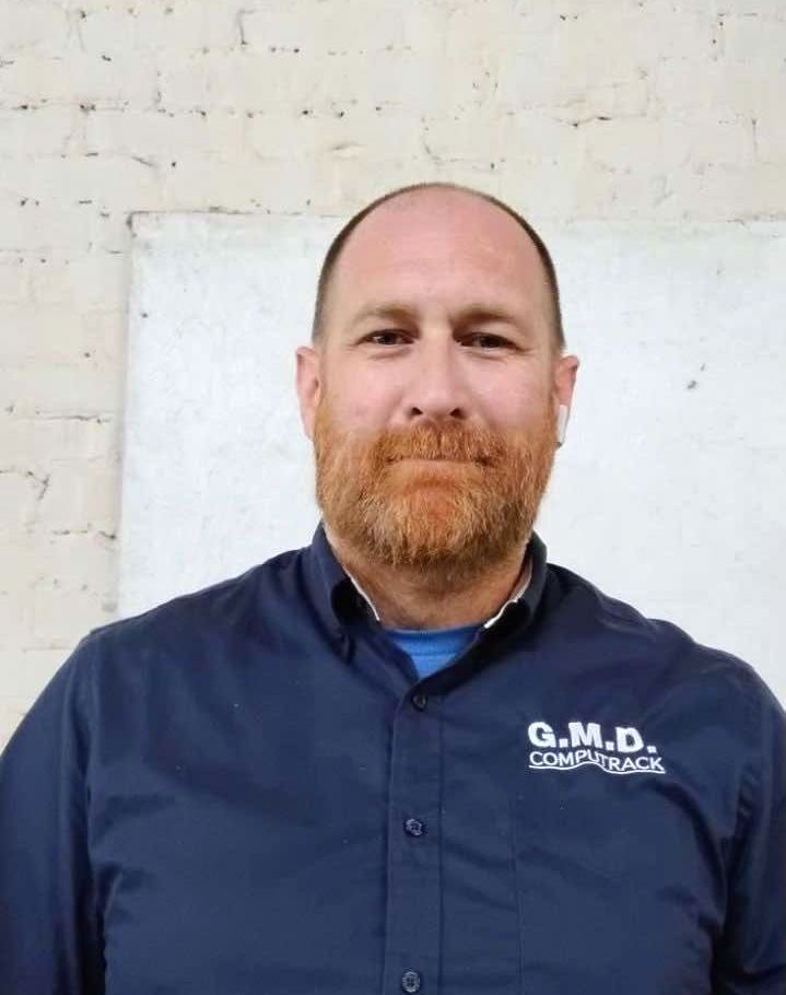 A man with a beard is wearing a blue shirt that says g.m.d.