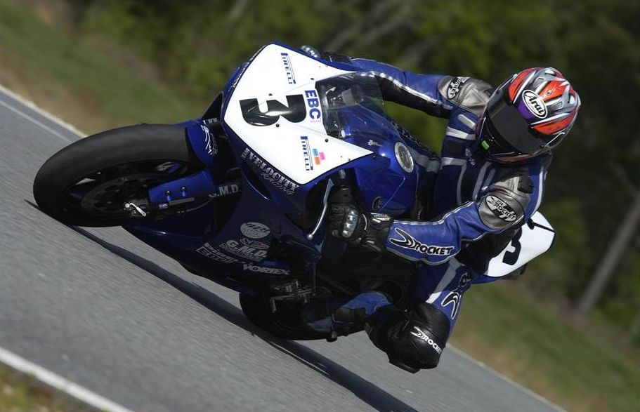 A man is riding a motorcycle with the number 3 on the front