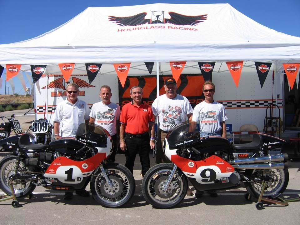 A group of men are standing in front of motorcycles with the number 1 and 9 on them
