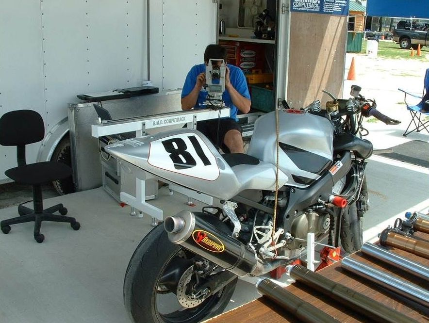 A man is taking a picture of a motorcycle with the number 81 on the back