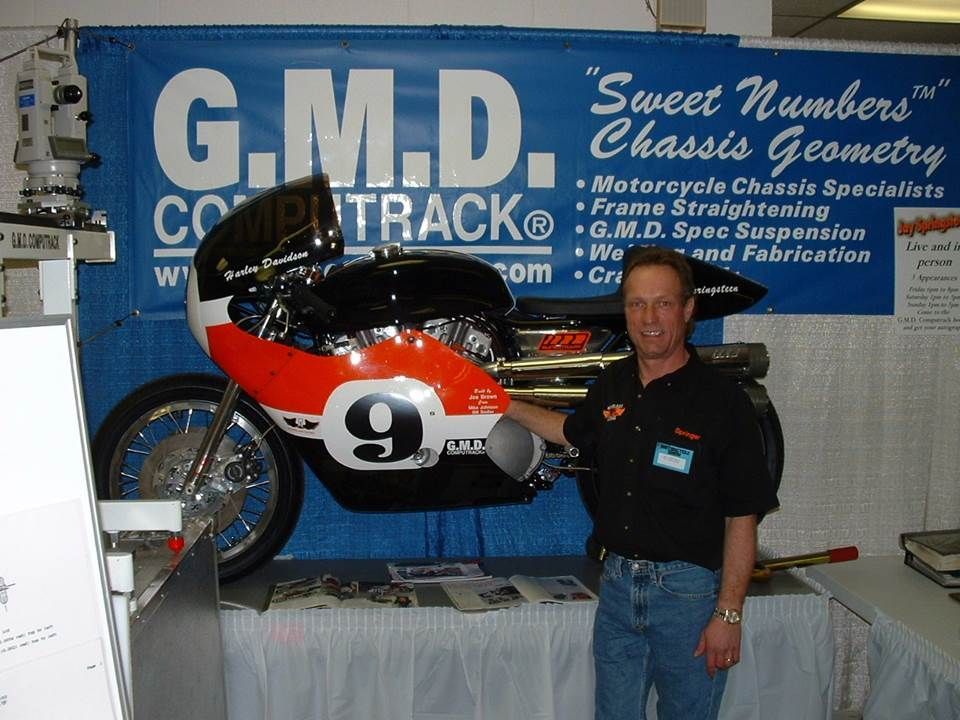 A man stands in front of a motorcycle with the number 9 on it