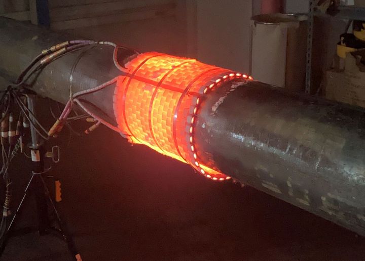 A metal pipe is being heated by a machine.