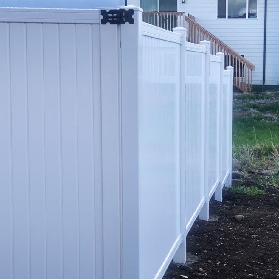 White vinyl fence, in front of a house with a wooden staircase.