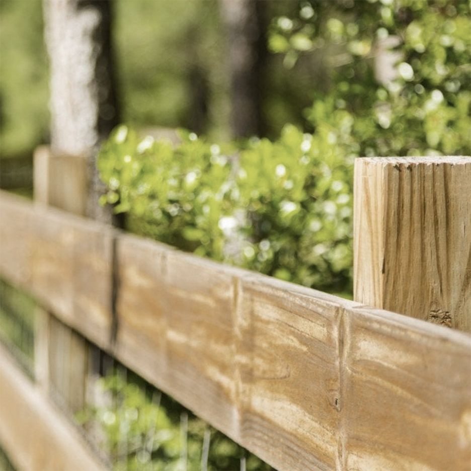 Wooden fence in a garden setting with green foliage in the background.