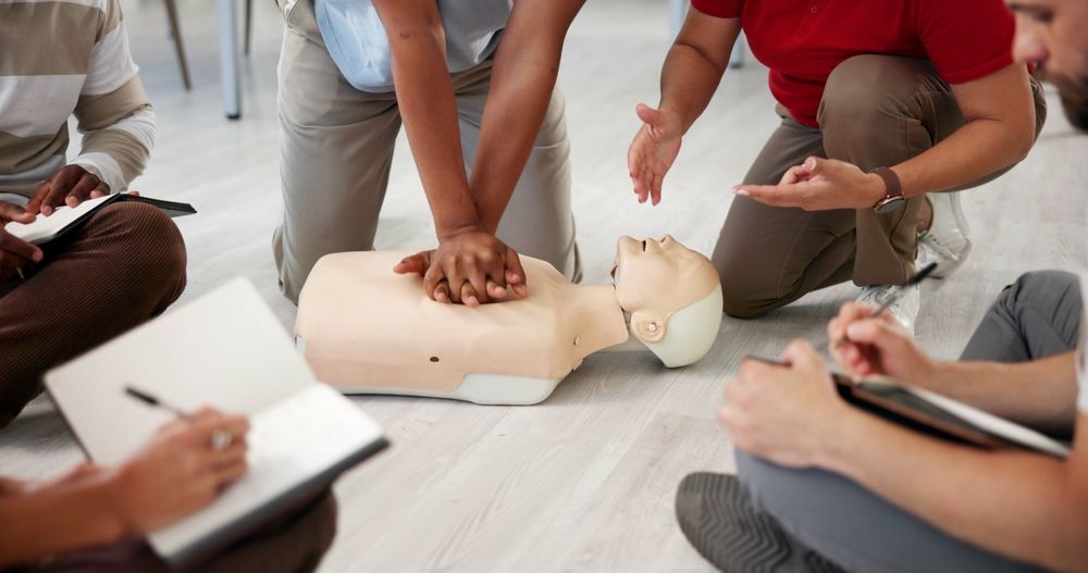 CPR training with a mannequin; instructor demonstrating chest compressions; students observing.