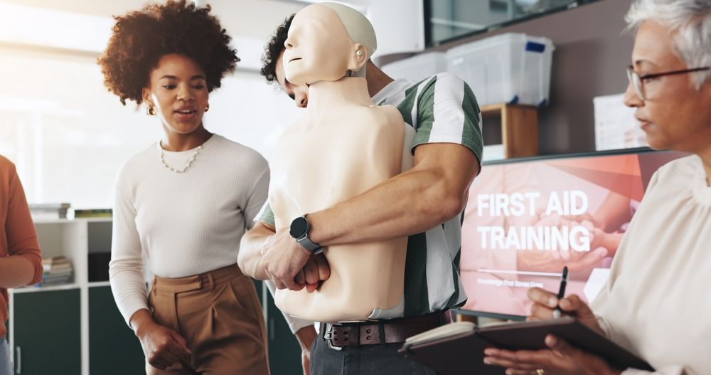 People practicing CPR on a mannequin during first aid training.