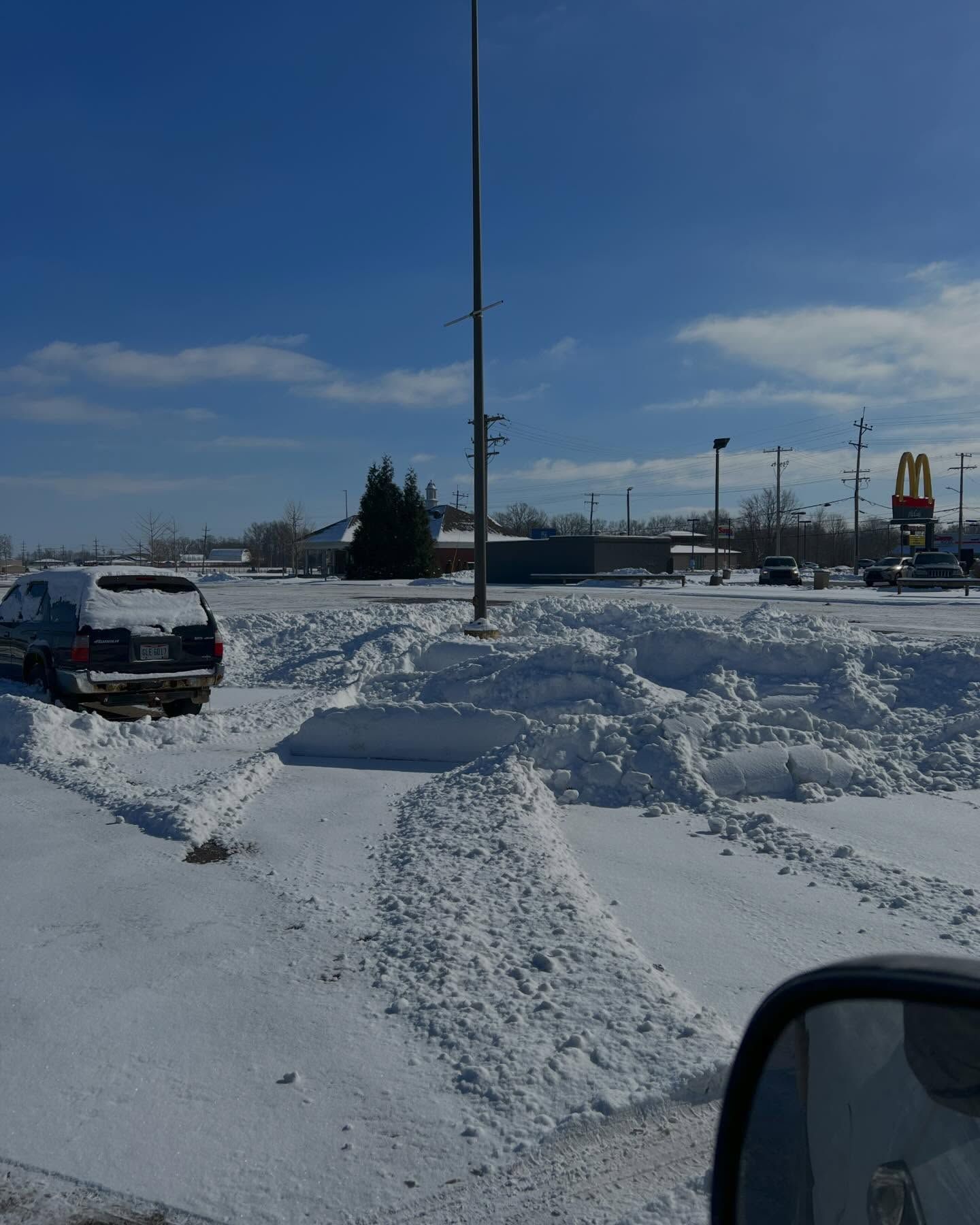 A snowy parking lot with a mcdonald 's in the background