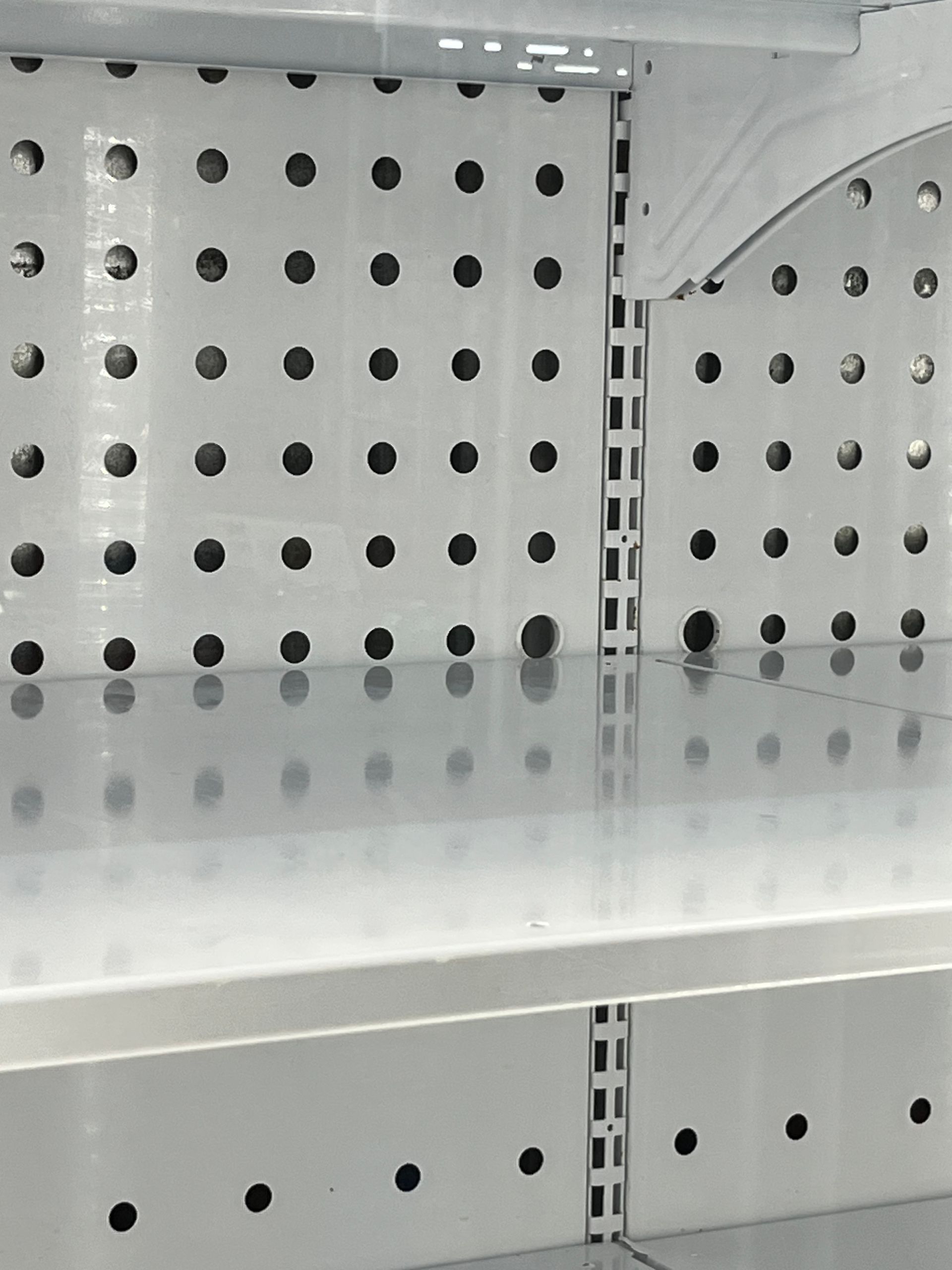 Empty white refrigerator shelving with multiple rows of evenly spaced holes.