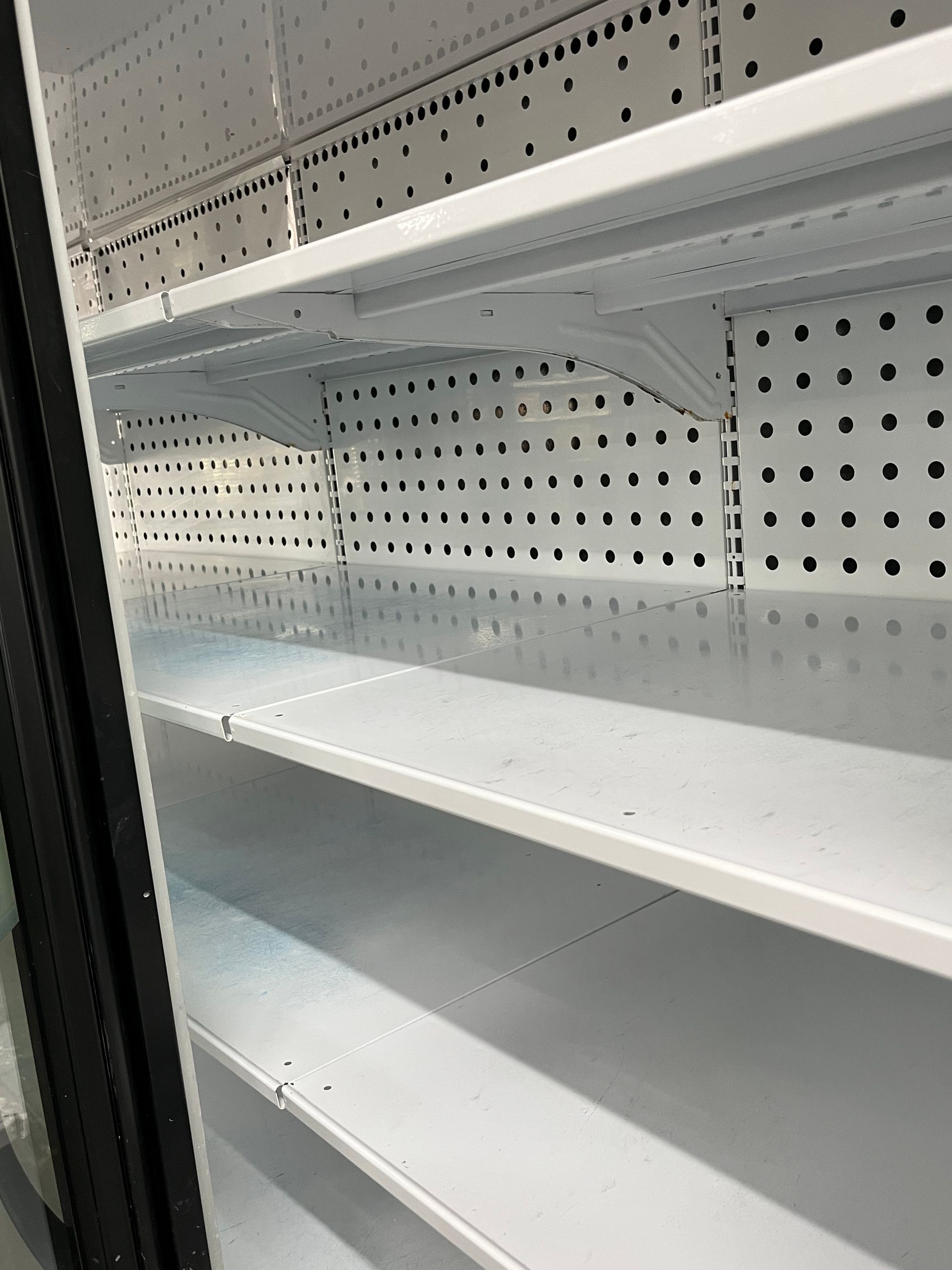 Empty white refrigerator shelves with black trim and a glass door.
