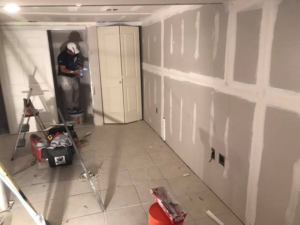 Interior room under construction, with trim, windows, and construction materials scattered around.