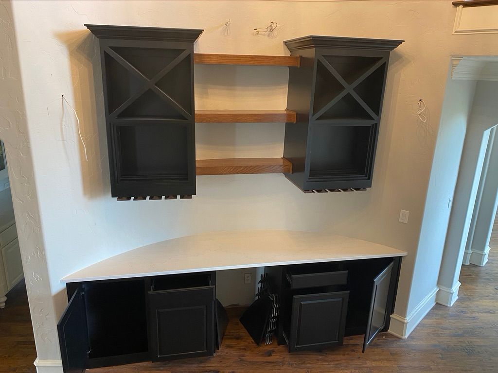 Built-in black cabinets with an X design above a white countertop and two lower cabinets, all set in a white wall.