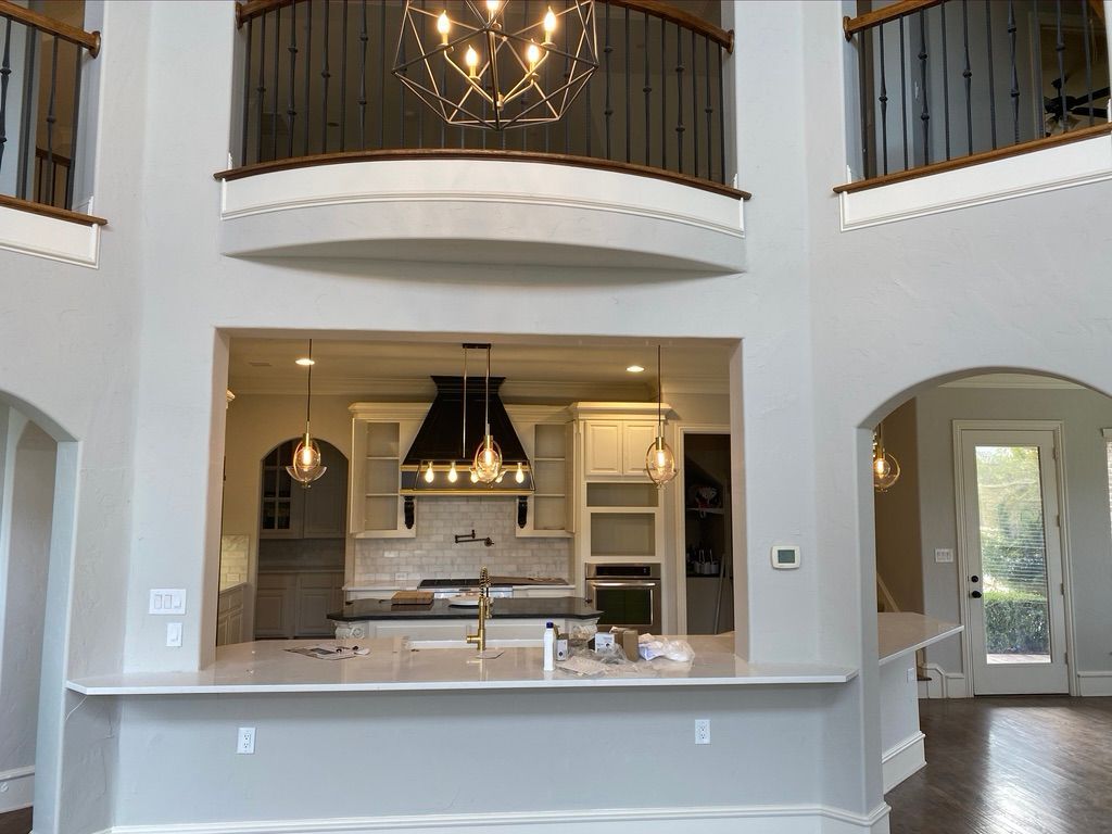Open-concept home with a kitchen visible from the living area. A balcony and a large chandelier are overhead.