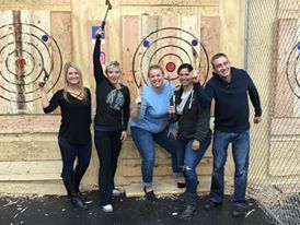 A group of people are posing for a picture in front of a wooden target.
