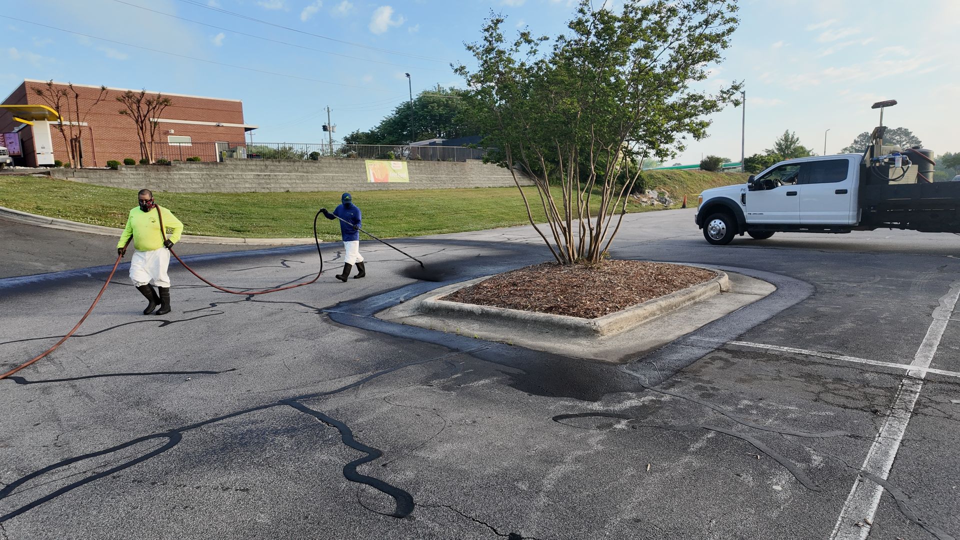 Two men are working on a parking lot with a truck in the background.