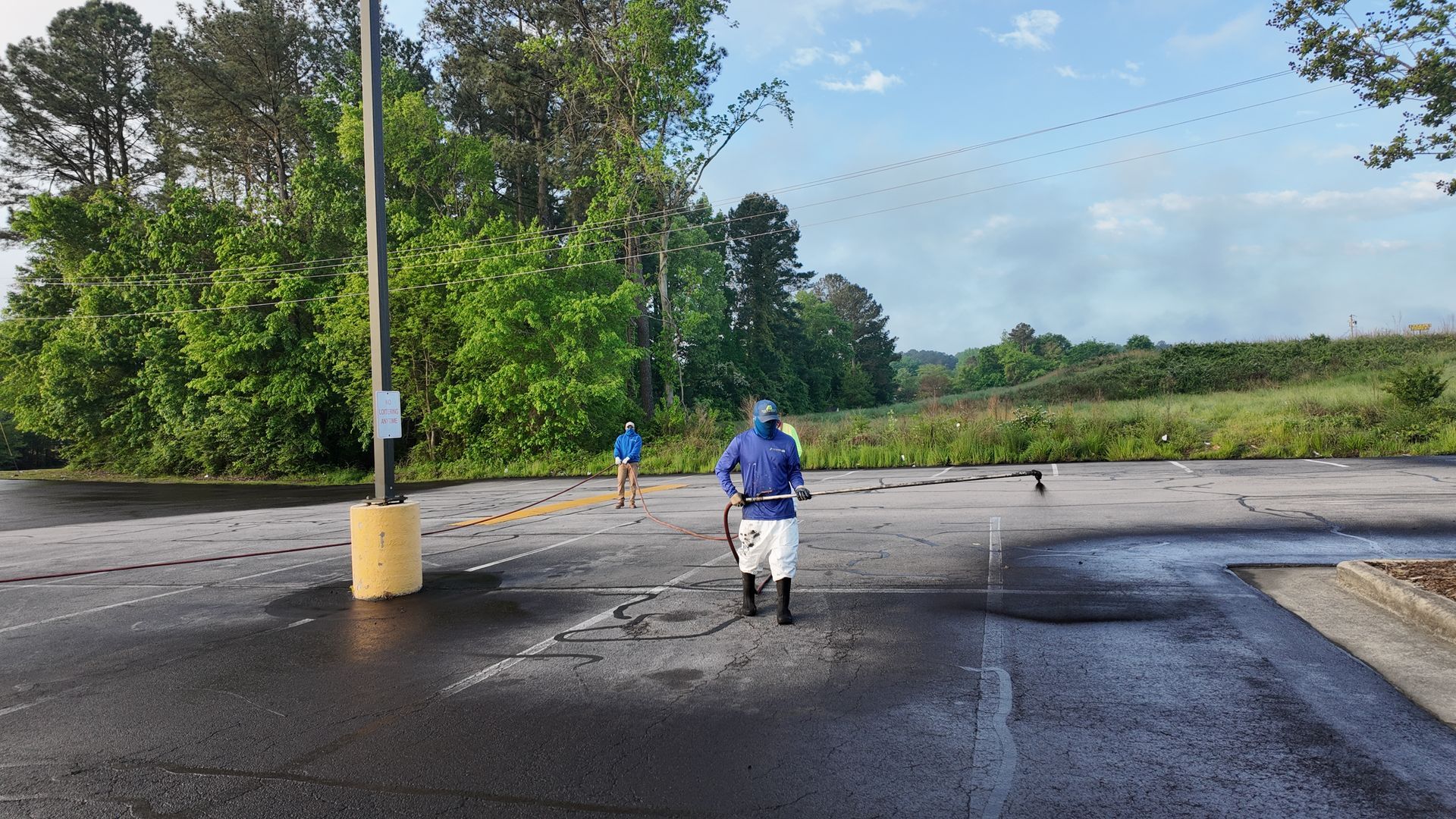 A man in a blue jacket is walking down a wet parking lot.
