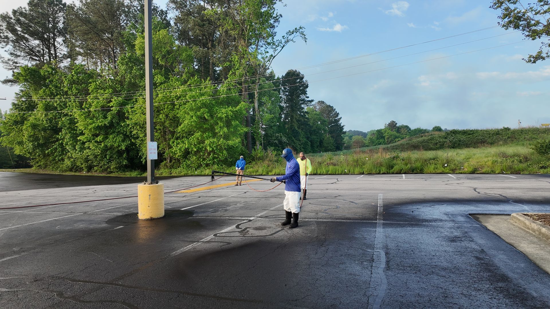 A person is spraying a parking lot with a hose.