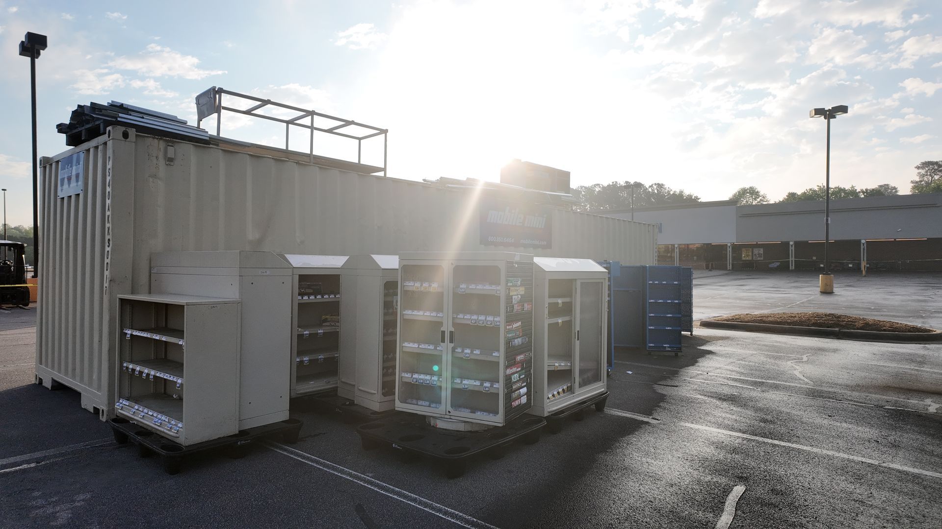A row of shipping containers are sitting in a parking lot.