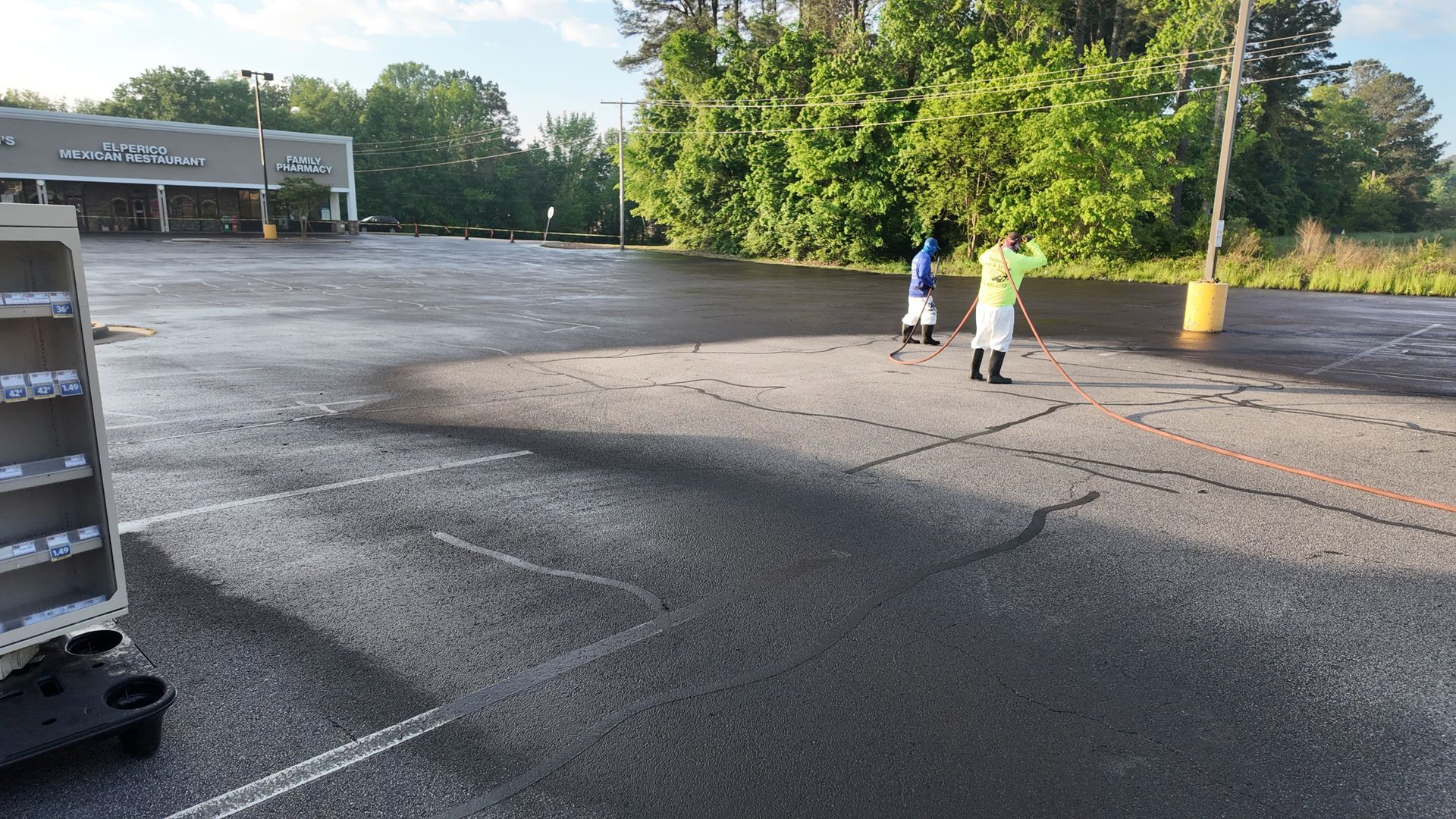Two people are standing in a parking lot near a store.