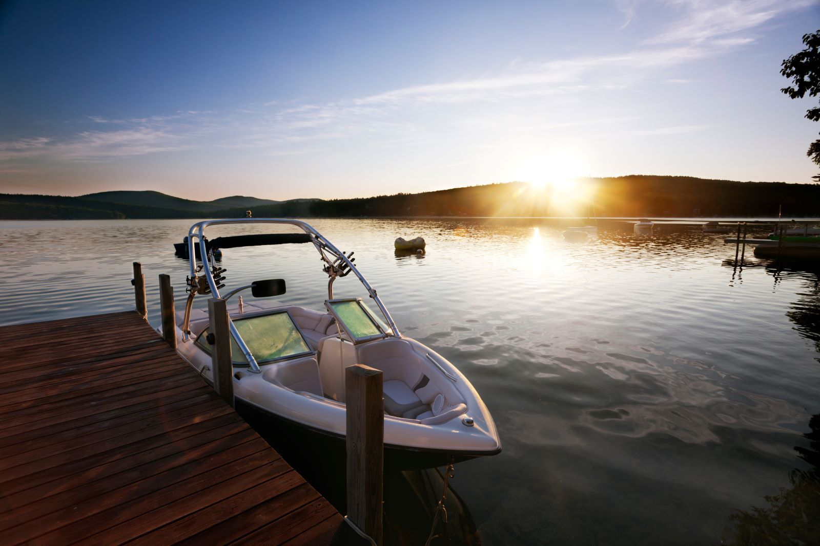 A boat is docked at a dock on a lake at sunset.
