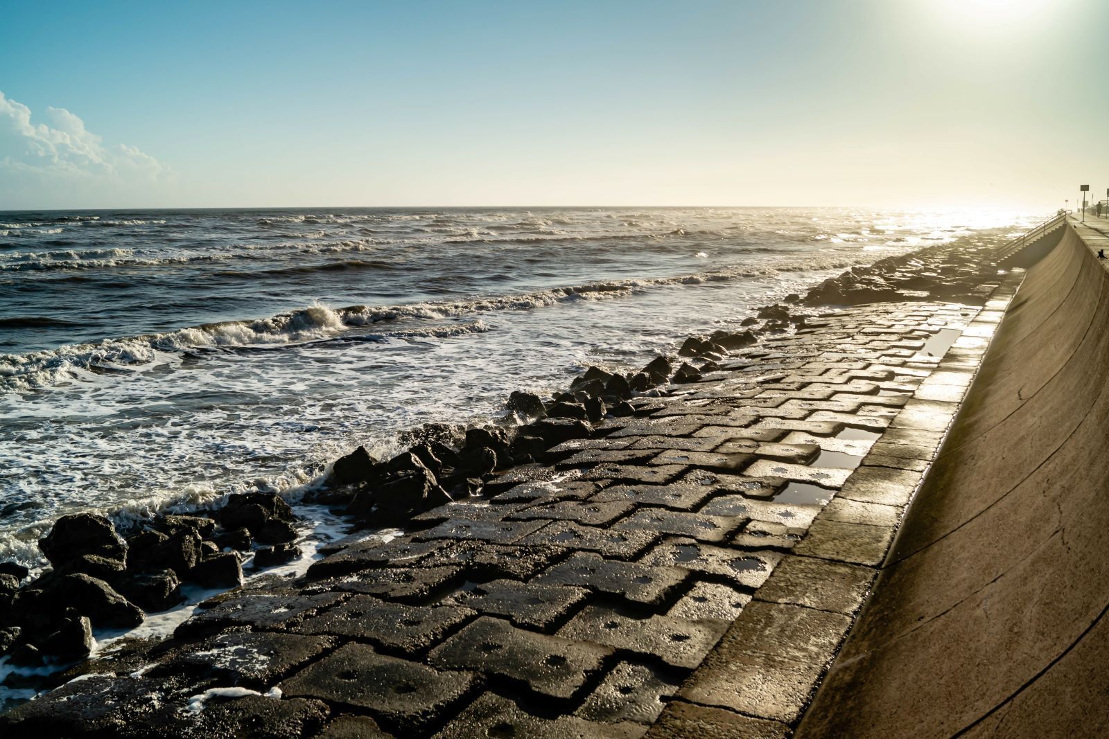 A brick boardwalk leading to the ocean on a sunny day