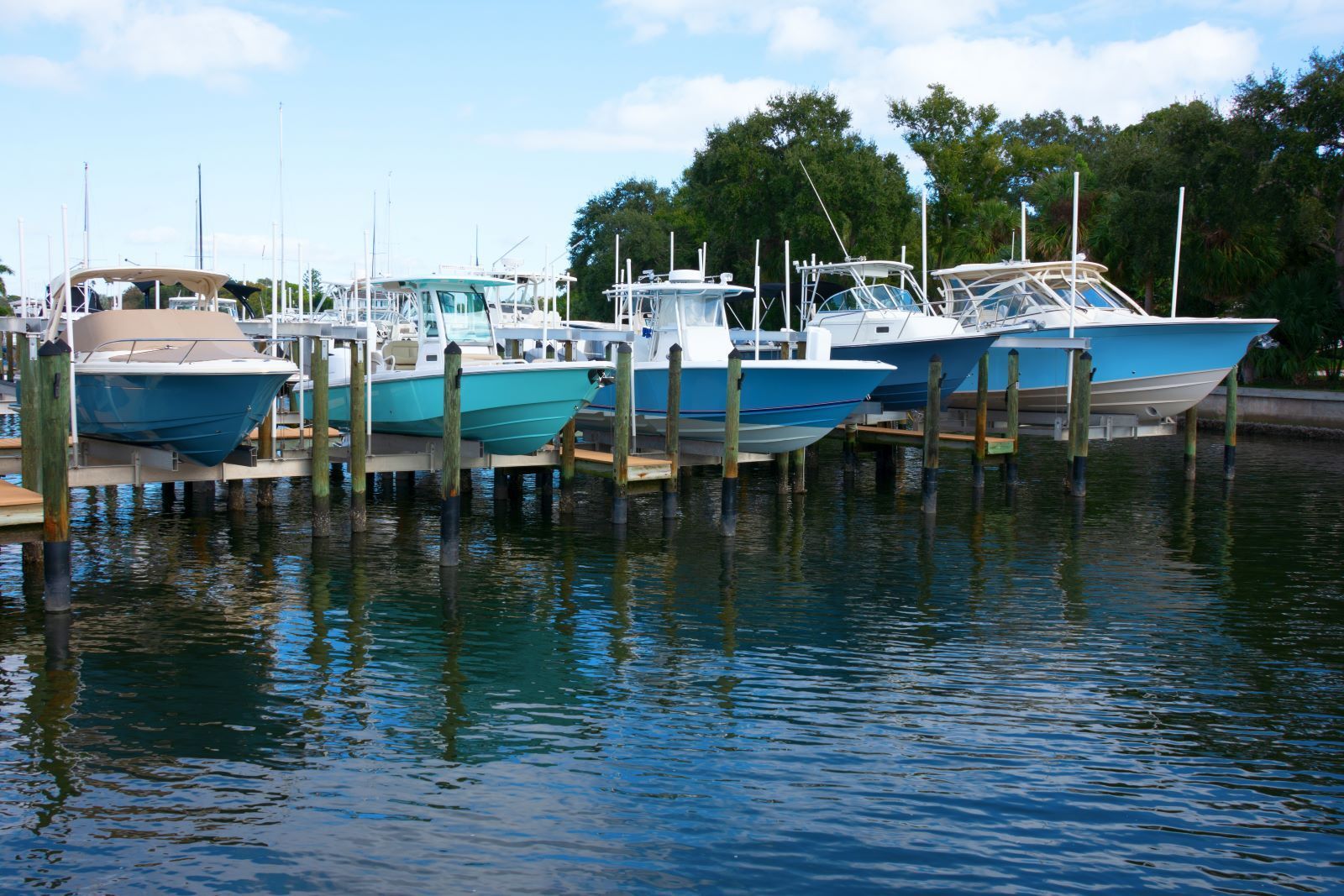 A row of boats are docked at a marina.
