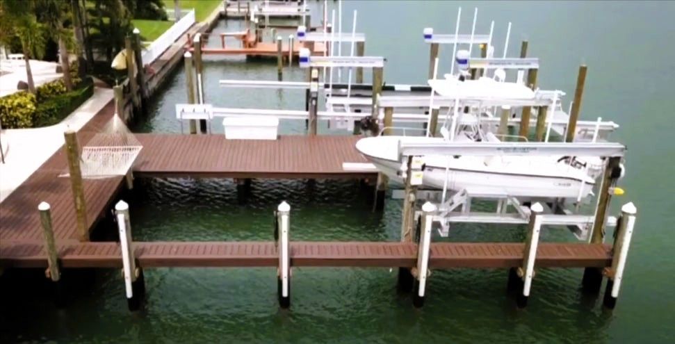 Aerial view of boat dock with white boat on lift and tropical landscaping