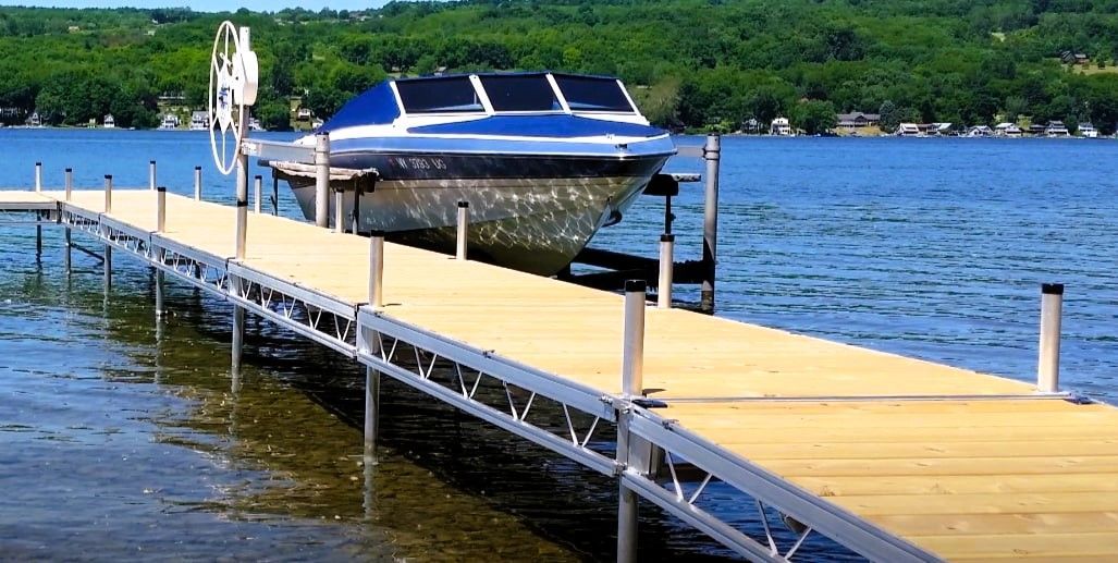 Boat hoisted on a lift at a wooden dock over a lake.