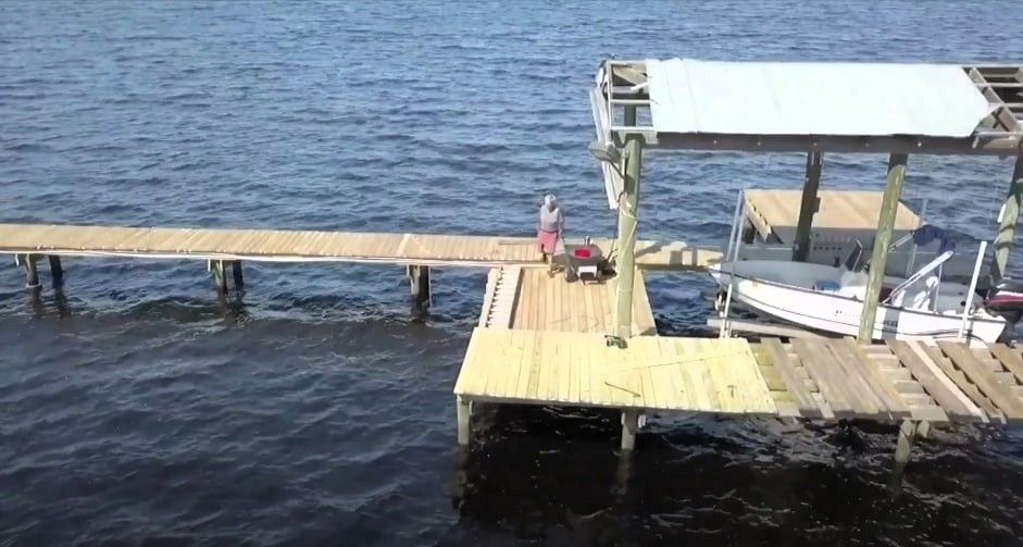 Person on wooden dock inspecting for boat dock repairs needed.