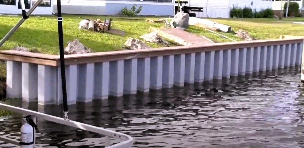 Waterside dock with a seawall and green lawn behind it.