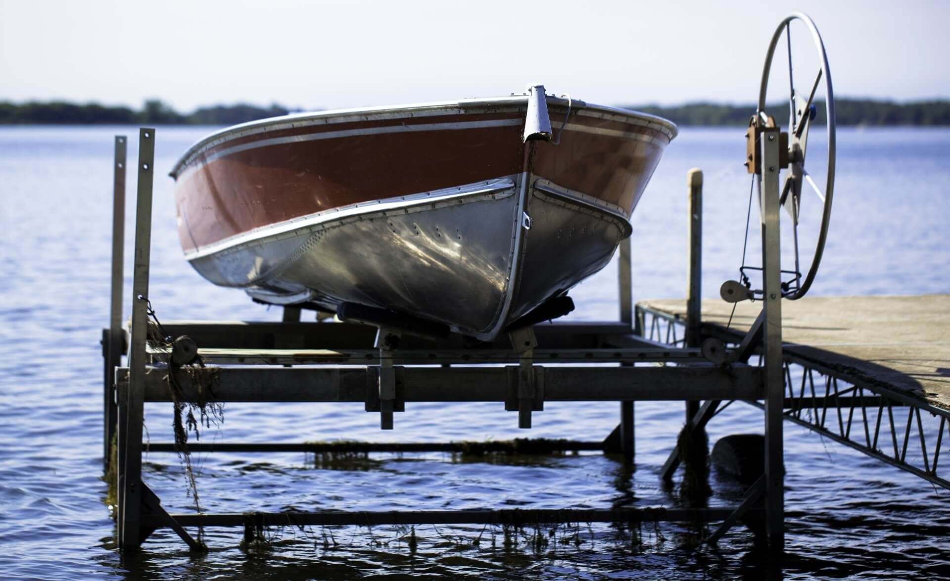 A boat raised from the water by a manual boat lift to protect it from damage and algae from staying on the water for too long