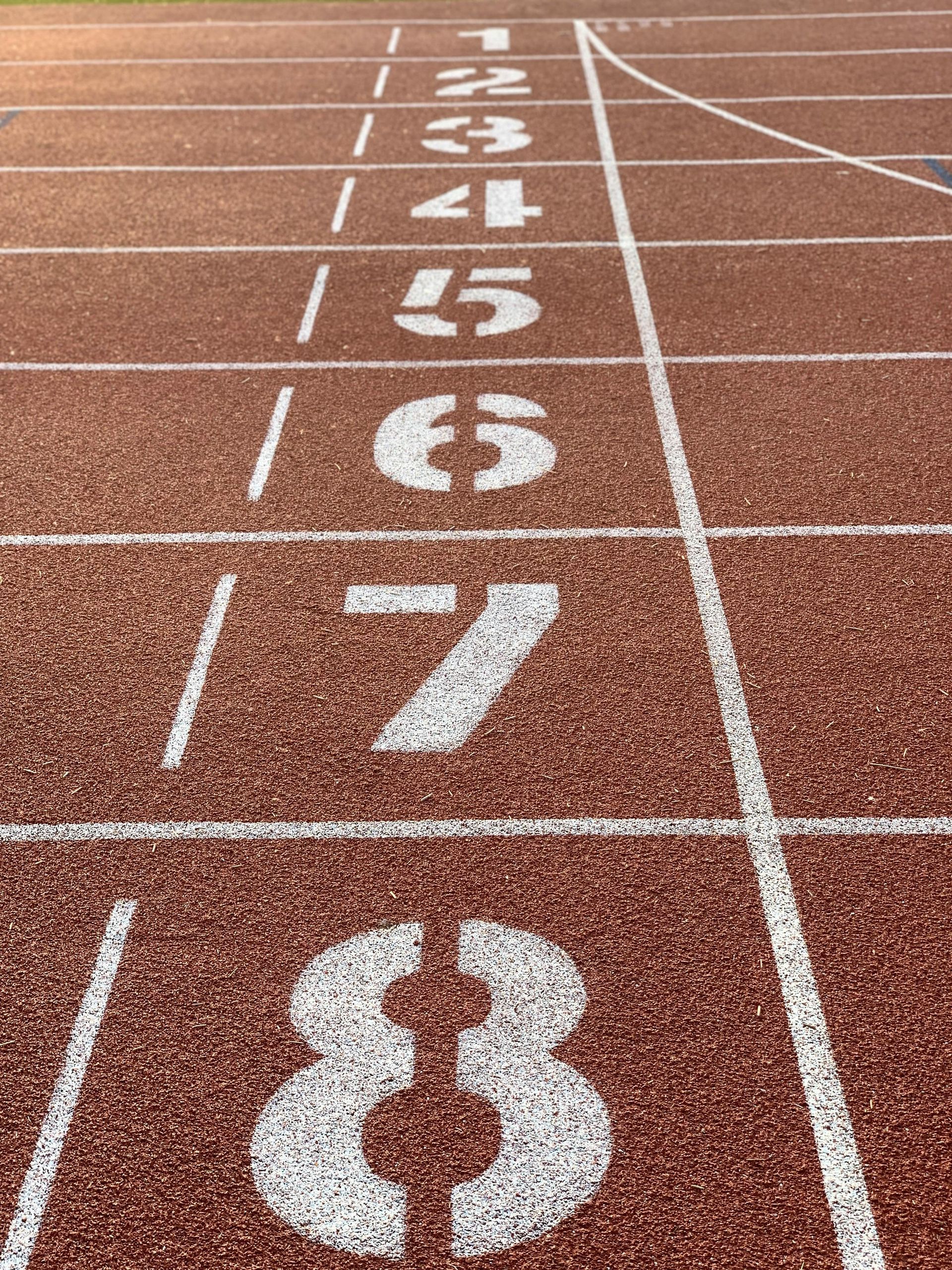 Starting blocks on a red track, lanes marked with white numbers 1 to 8, ready for a race.