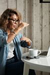 A woman is sitting at a table with a laptop and a cup of coffee.