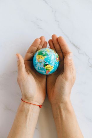 A person is holding a small globe in their hands.