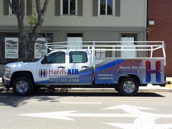 A harris air truck is parked on the side of the road in front of a building.