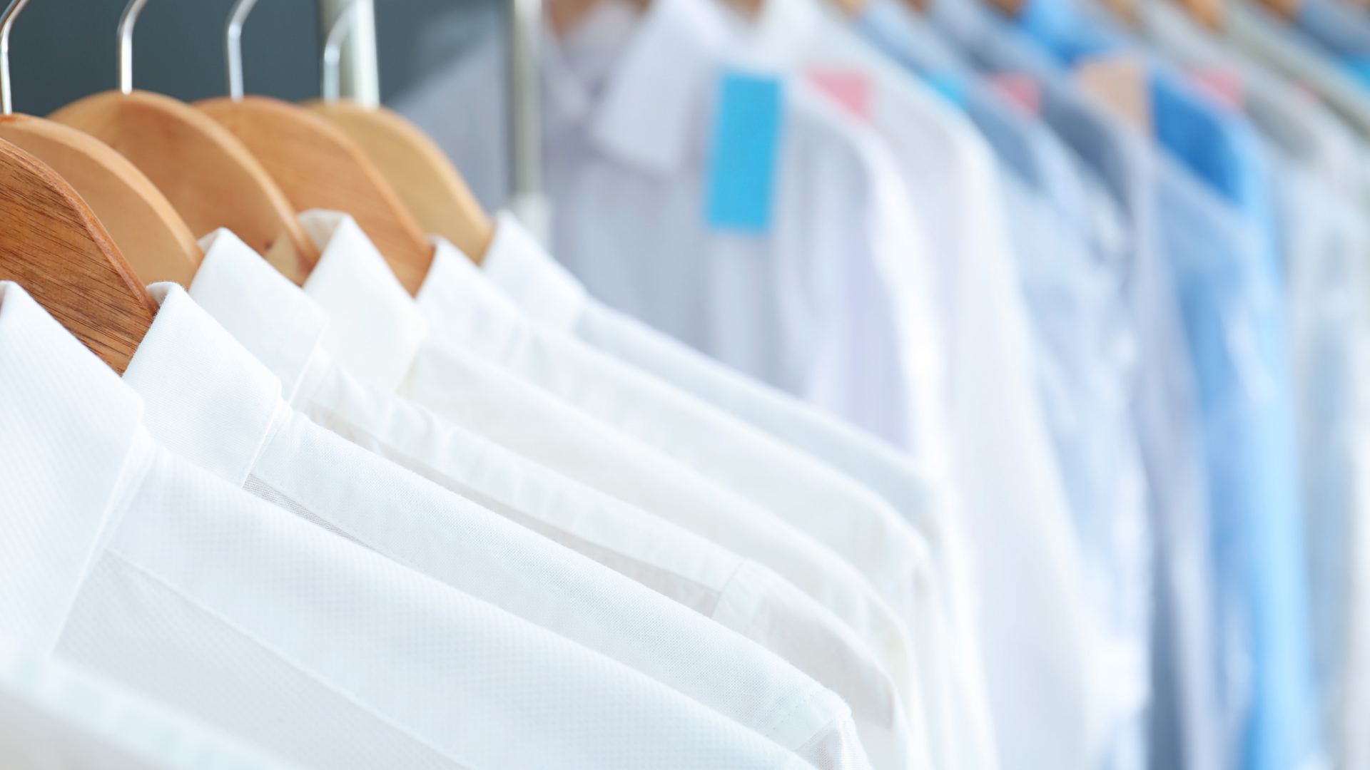 Shirts in plastic dry cleaning bags hang on a circular rack.